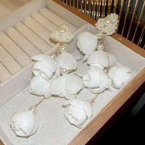 Primo piano di eleganti orecchini a fiore in rete bianca con nappa di perle e scatola