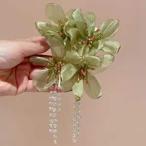 Close-up detail of light green mesh flower drop earrings with crystal bead tassels.