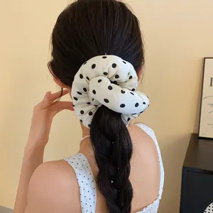 Vista trasera de modelo con coletero de lunares blancos en el pelo trenzado