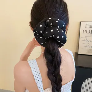 Elegante coletero de tela negra con lunares blancos usado en una coleta trenzada.