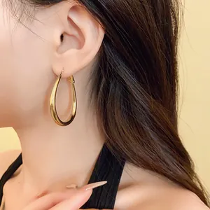Detail shot of elegant gold plated oval hoop earrings shown being worn by a model