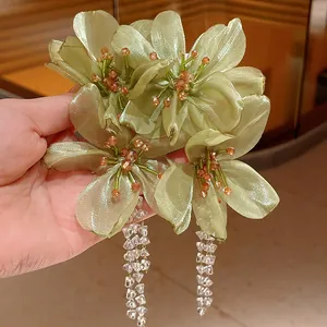 Detailed shot of elegant light green organza flower earrings with long crystal tassel drops