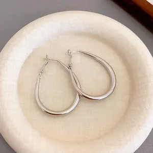 Detailed view of minimalist silver plated oval U-shaped hoop earrings on a tray