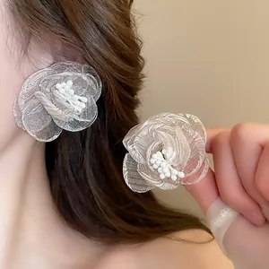 Primo piano di eleganti orecchini a fiore in rete con centro di perle indossati da una modella