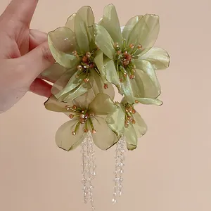Close-up view of elegant green mesh flower earrings with hanging crystal stone tassels.