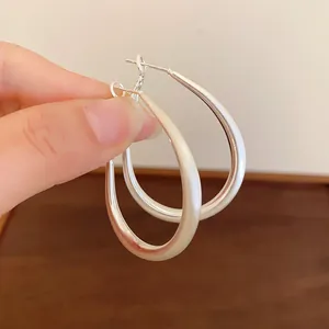 Close-up detail view of minimalist silver U-shaped oval hoop earrings for women