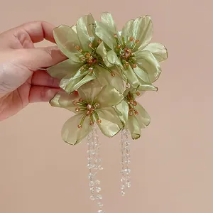 Close-up detail of light green mesh flower earrings with long crystal beaded tassels.