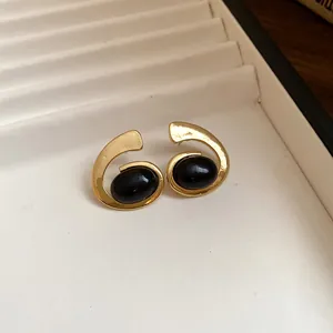 Gros plan de boucles d'oreilles spirales dorées vintage avec pierre cabochon noire