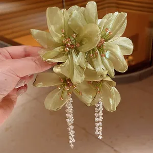 Detailed view of handmade green mesh flower earrings with elegant long crystal tassels