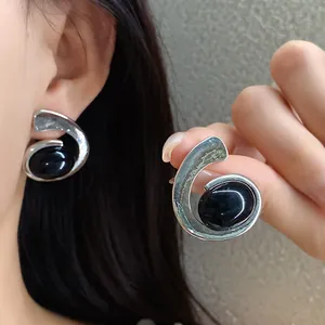 Gros plan sur des boucles d'oreilles spirales vintage avec pierre cabochon noire