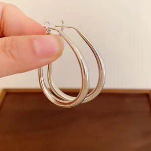 Close-up detail of polished silver U-shaped hoop earrings held to show scale and finish.