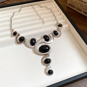 Gros plan d'un collier spirale géométrique vintage avec pierres noires et argent