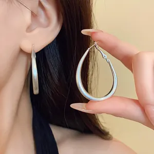 Detailed close-up of minimalist matte silver teardrop hoop earrings on a model's ear