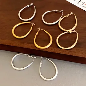 Detailed view of oval U-shaped hoop earrings in gold and silver textured finishes.