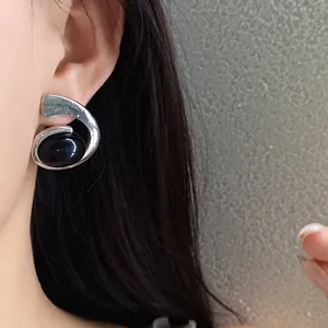 Gros plan de boucles d'oreilles vintage en spirale avec pierre ovale noire sur un modèle.