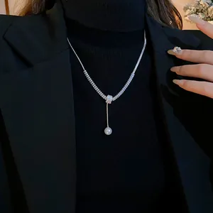 Detail shot of elegant silver-toned pearl and zircon necklace on black turtleneck.