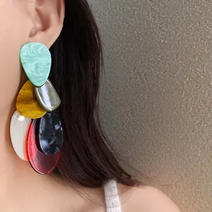 Close-up view of colorful layered acrylic teardrop earrings showing the texture and wearing effect