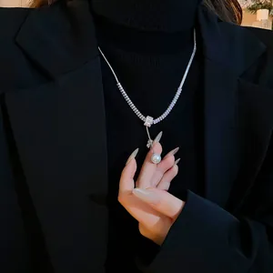 Close-up detail of an elegant pearl and zircon necklace worn on a black turtleneck