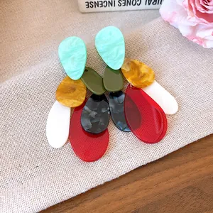 Close-up of retro oversized acrylic marbled earrings with multi-color drop designs