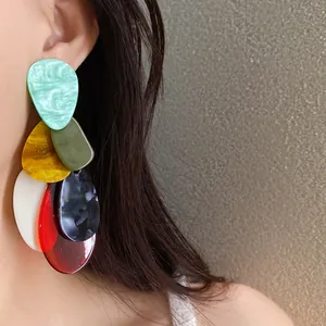 Close-up view of colorful marbled acrylic statement earrings on the model's ear.