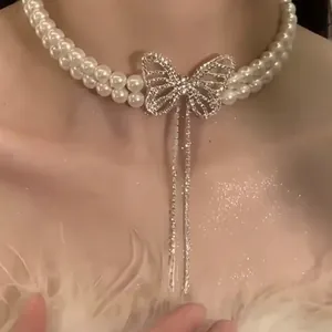 Elegant double-layer pearl necklace with rhinestone butterfly pendant worn by a model