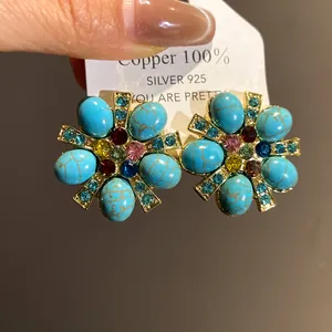Dettaglio di orecchini a fiore vintage con pietre blu e cristalli colorati
