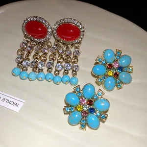 Primo piano di orecchini vintage decorati con fiori turchesi e nappine di cristalli.