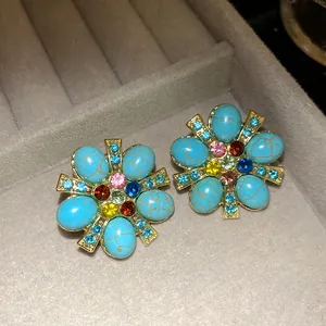 Macro dettagliata di orecchini vintage a fiore con pietre turchesi e cristalli colorati