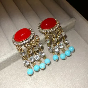 Dettaglio macro di orecchini vintage in oro con pietre rosse e perline turchesi
