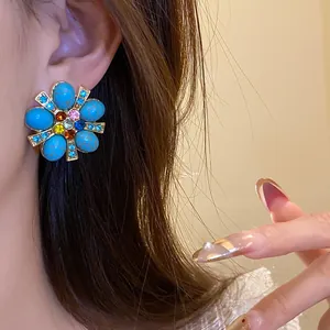 Dettaglio degli orecchini vintage a fiore con pietre turchesi e cristalli colorati