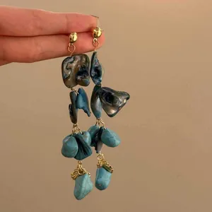 Dettaglio di orecchini pendenti bohémien con conchiglie blu e perline di pietra