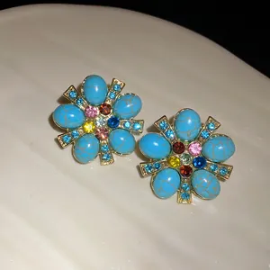 Primo piano di orecchini vintage a forma di fiore con pietre turchesi e strass vari