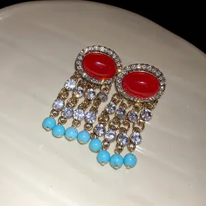 Dettaglio di orecchini vintage con pietre rosse, strass trasparenti e perline turchesi