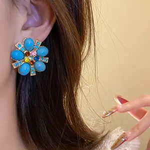 Orecchini a perno vintage a forma di fiore con pietre turchesi e strass colorati al lobo.