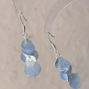 Macro view of blue gradient shell petal earrings with silver hooks for an elegant look.