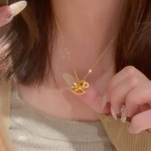 Close-up view of a minimalist gold rocking horse pendant necklace worn on a woman's neck