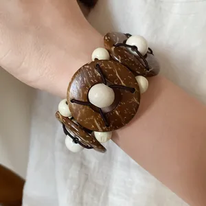 Dettaglio di un braccialetto in stile etnico con perle di legno e noce di cocco.