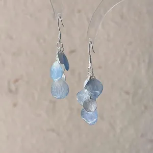 Detail of gradient blue petal earrings with silver textured discs and ear hooks