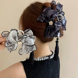 Detalle de la pinza de pelo de estilo chino con lazo, borla y flor de camelia.