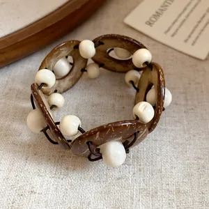 Dettaglio macro del bracciale boho con anelli di cocco e perle bianche