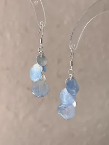 Detailed macro view of elegant light blue shell petal drop earrings with silver hooks.
