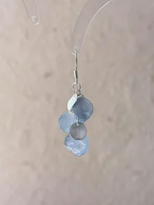 Close-up of handmade gradient blue petal earrings with textured silver-toned metal disks.