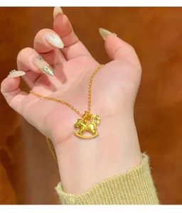 Detailed close-up showing a golden rocking horse pendant necklace resting on a palm