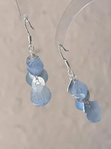 Detailed close-up of light blue gradient petal shell earrings with textured silver discs.