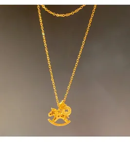 Detailed view of a golden rocking horse pendant necklace on a dark grey background