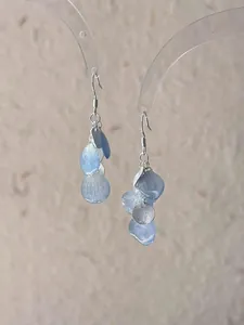 Macro detail of fresh blue gradient shell petal earrings featuring a silver disc charm