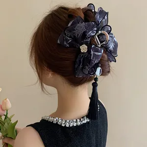 Vista detallada de una elegante pinza para el cabello con lazo negro y borla en un moño clásico