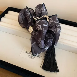 Detalle de una pinza para el pelo con lazo de estilo chino, borla negra y flor de camelia