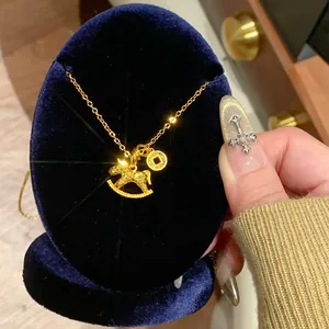 Macro detail of a shimmering golden rocking horse necklace presented on a blue velvet display