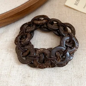 Dettaglio macro del bracciale a maglie in guscio di cocco marrone con trama rustica